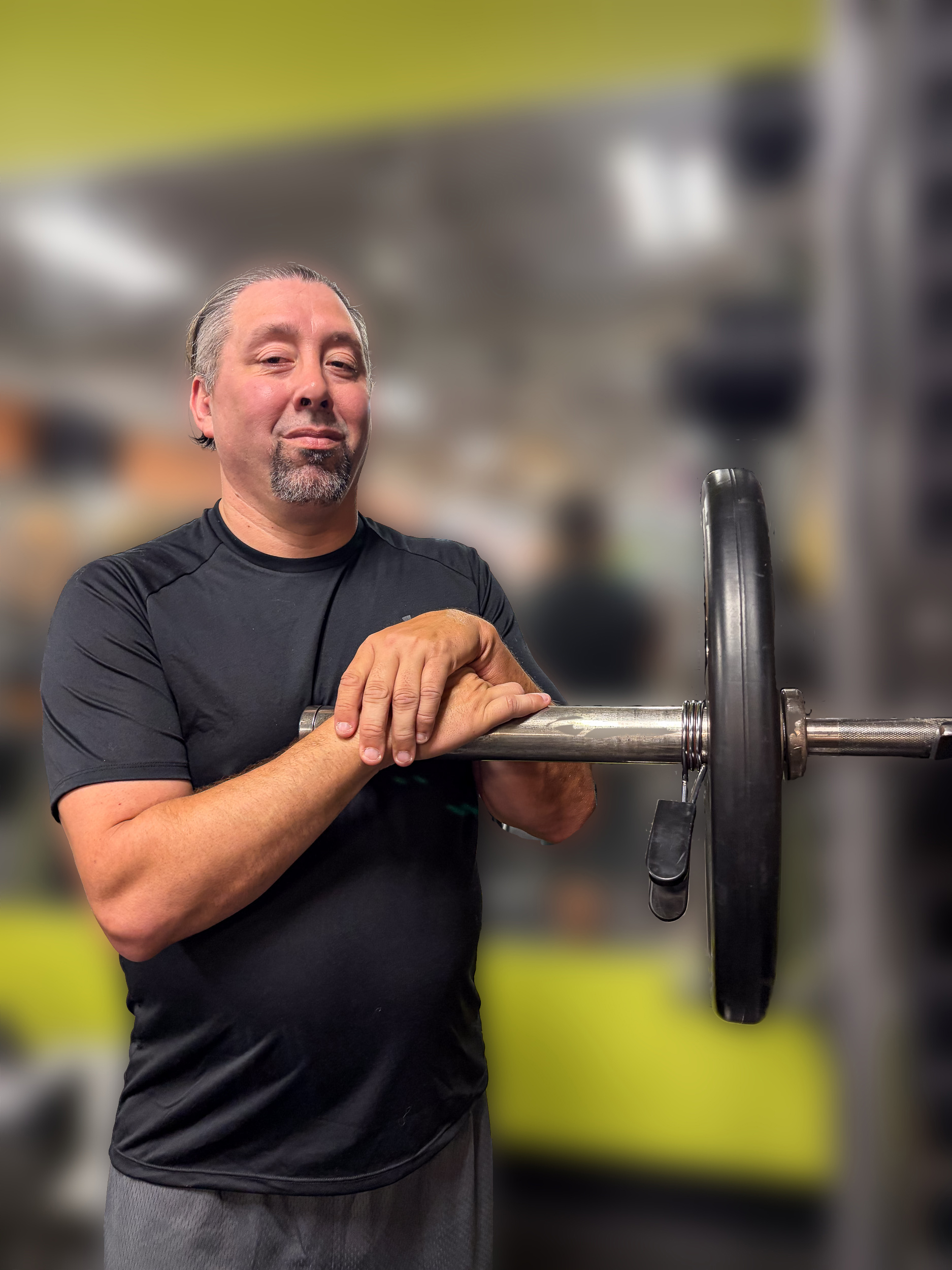 Lewis Mendez standing beside a loaded barbell in a gym